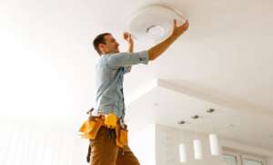 Electrician installing ceiling light.