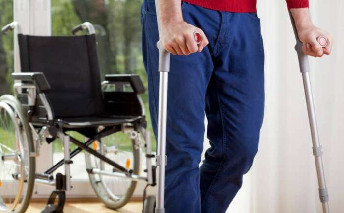 Man at home using crutches.