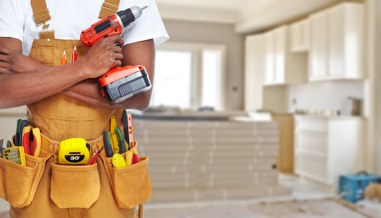 Handyman holding his tools including a drill and pliers