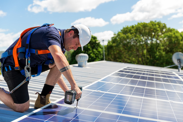 Solar installer installing solar panels with a hardhat on