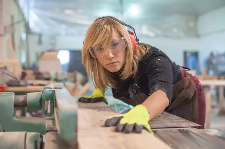 Female carpenter sanding wood