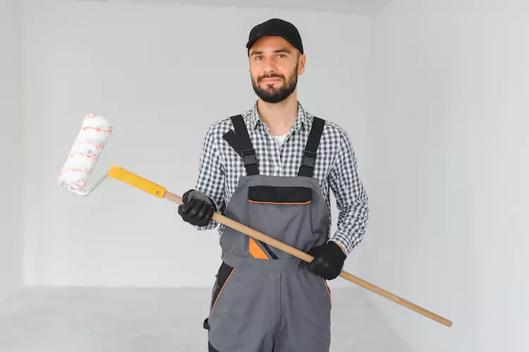 Painter holding a roller in a white room