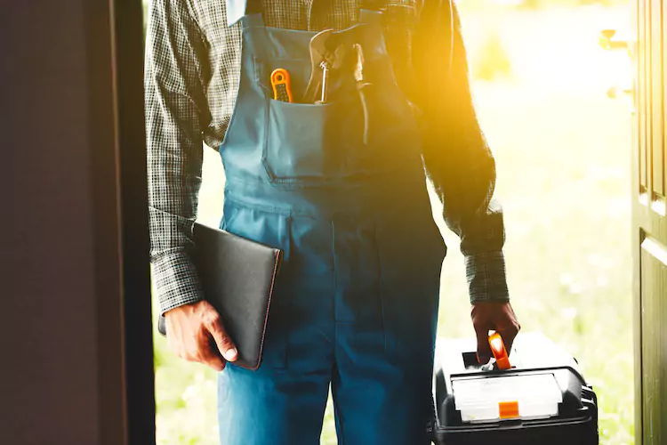 Plumber in a doorway holding a toolbox