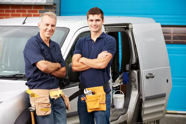 Plumbers in front of their commercial vehicle