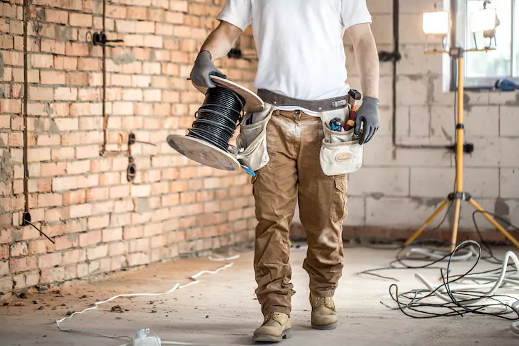 Insured electrician uncoiling cable in a commercial construction site