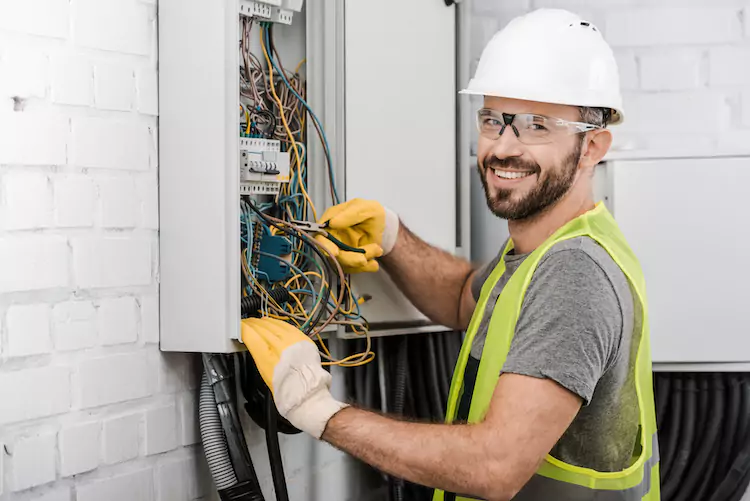 Insured electrician opening a fuse box smiling
