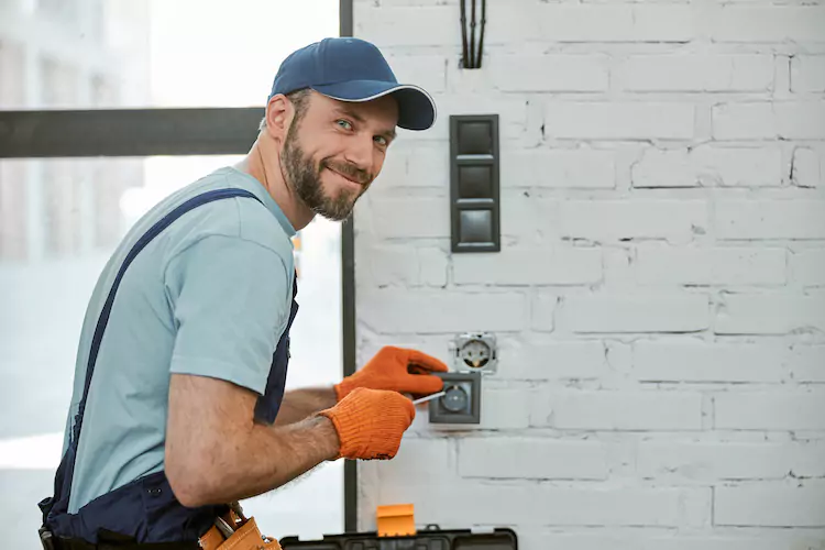 Insured electrician opening a socket smiling