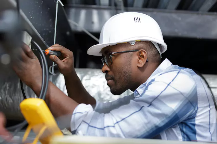 Insured electrician using a screwdriver to open a fusebox without gloves