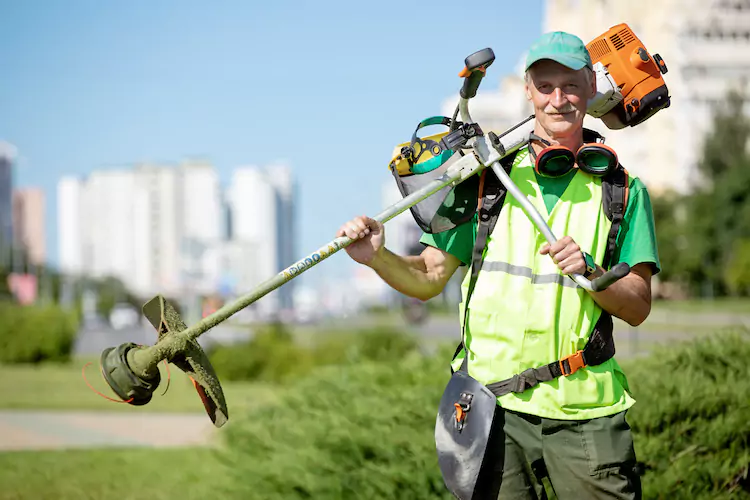 Middle-aged gardener holding a whipper snipper over his shoulder