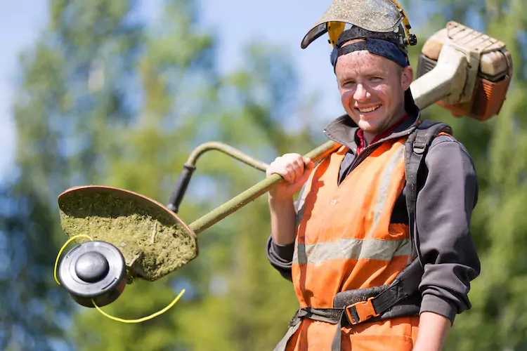Gardener holding a whipper snipper over his shoulder and smiling