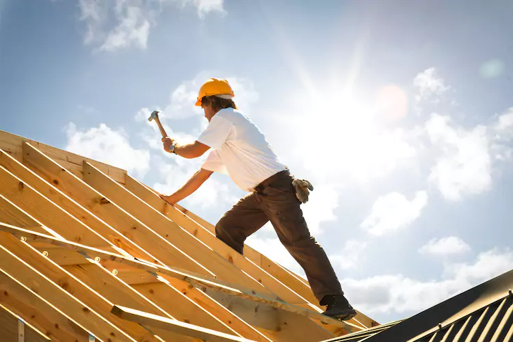 Insured roofer hammering into a wooden beam
