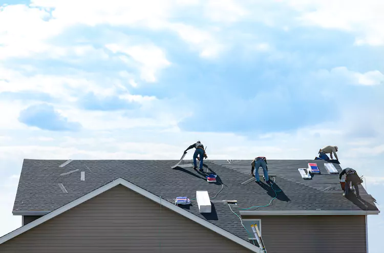 Four roofers nailing in tiles on a residential roof