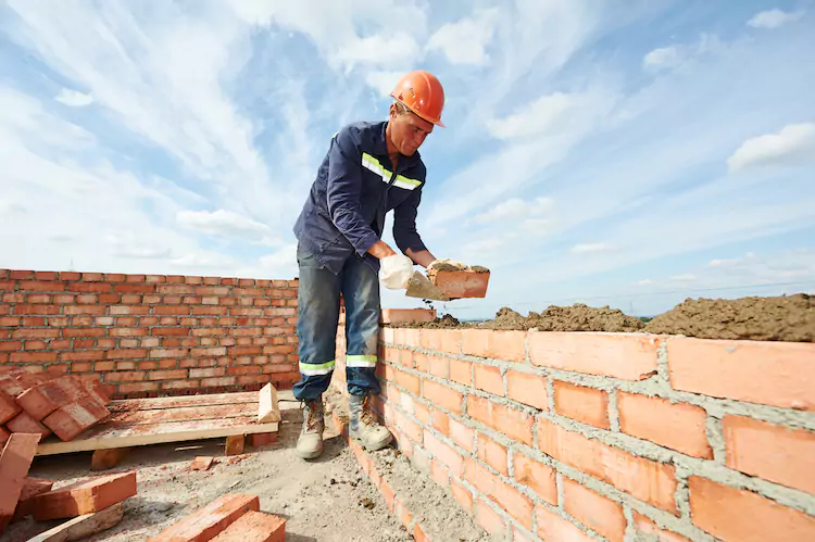 Insured bricklayer laying a brick on a construction site