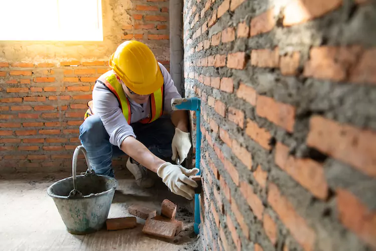 Insured bricklayer looking at grouting