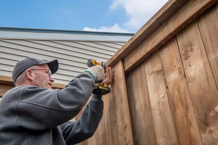 Insured fencer installing a wooden fence