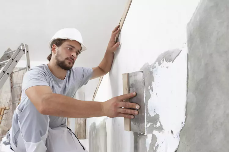Insured plasterer plastering a wall