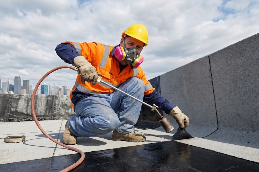 Insured waterproofing contractor on a roof in safety gear