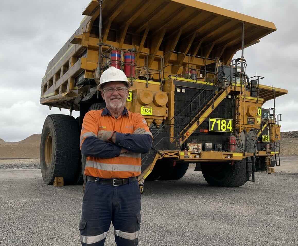 Insured mining contractor standing in front of a large piece of mining machinery